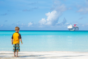 Little boy on the shore looking at the ship