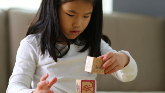 Young girl stacking Chinese blocks