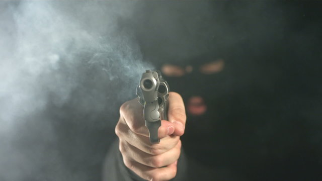 Criminal shoots gun directly at camera, slow motion