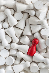 Background of white game figurines with one red figurine among them
