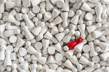 Background of white game figurines with one red figurine among them
