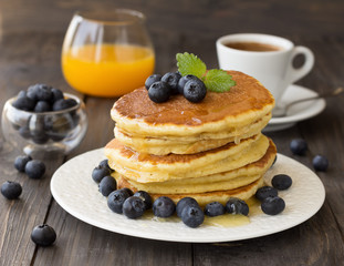 Pancakes with fresh blueberries and honey on wooden table