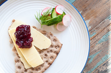 Scandinavian crisp bread topped with cheese and lingonerry jam served with a salad of cucumber, radish and dill.