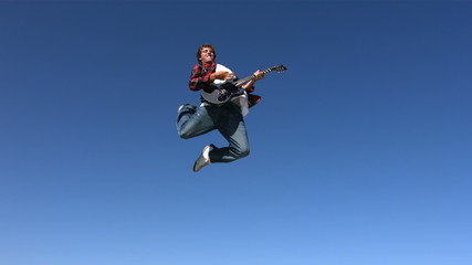 Teen boy jumps into sky with guitar, slow motion - Powered by Adobe
