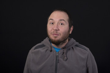 young man making a funny face isolated on black background