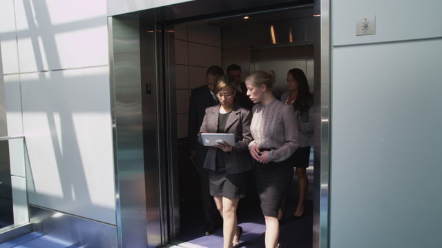 Business people walk out of elevator
