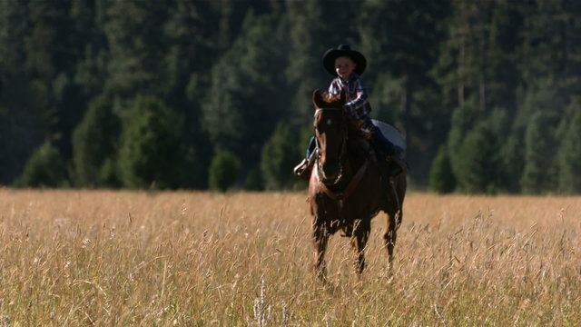 Young cowboy riding horse, slow motion