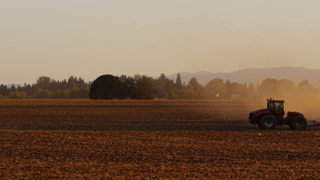 Tractor plowing field at sunset