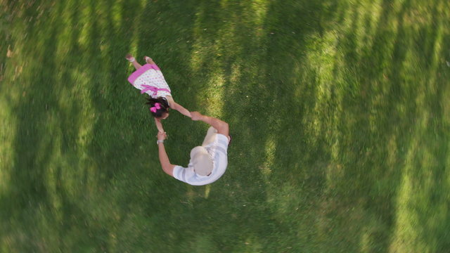 Overhead shot of father spinning around with daughter in yard
