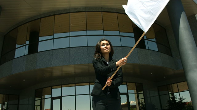 Businesswoman in front of office building waving white flag