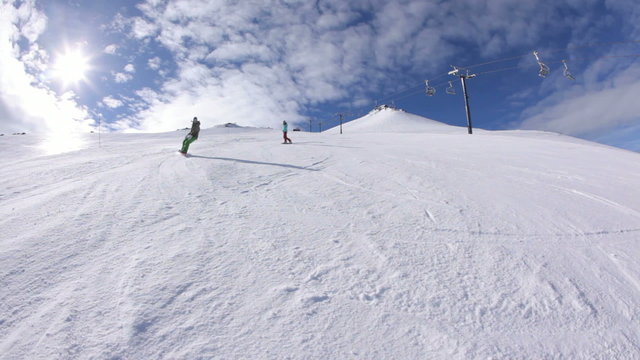 Four snowboarders ride down ski slope