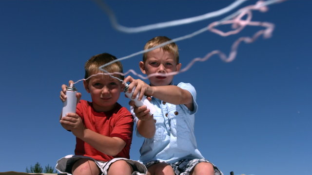 Two young boys shoot silly string, slow motion