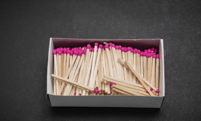 Closeup view of many pink matchsticks in carton box on dark grey background 