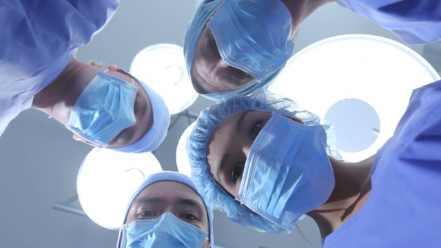Group of surgeons look down at patient