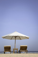 Tropical beach scenery with parasol and chairs 
