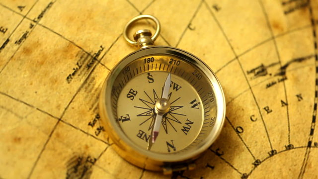 Golden compass on antique map