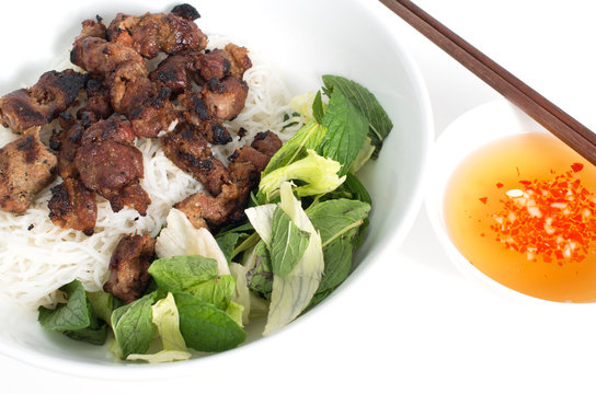 Vietnamese grilled pork skewers on vermicelli and bowl of fish s