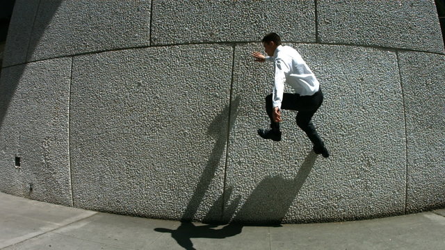 Business man jumps off wall, slow motion