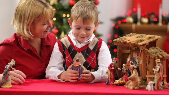Mother helps son set up Christmas nativity scene