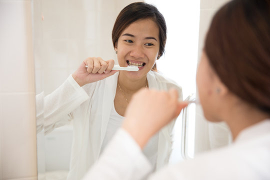 Beautiful asian woman brushing her teeth happily