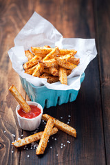 Roasted vegetables (potatoes and celery root) in ceramic basket and tomato sauce, selective focus