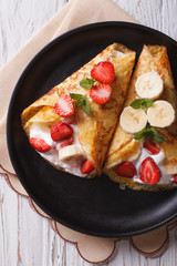 crepes with strawberries, bananas and cream closeup vertical top view
