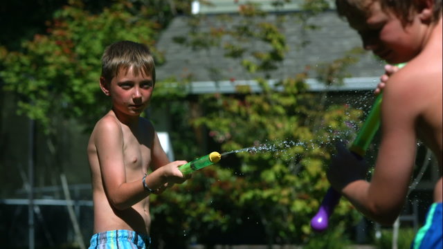 Two young boys having squirt gun fight in slow motion