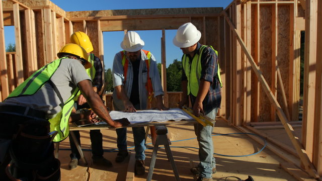 Group of construction workers look at plans