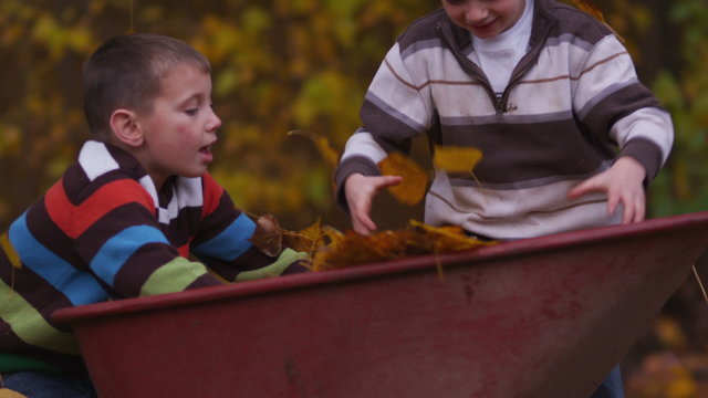 Two young boys throwing fall leaves, slow motion