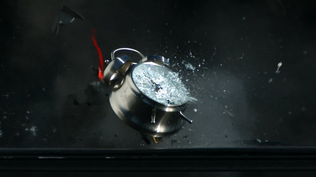 Ringing alarm clock is shot with gun, slow motion