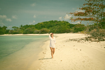 Fototapeta na wymiar Woman walking on exotic beach - retro style photo