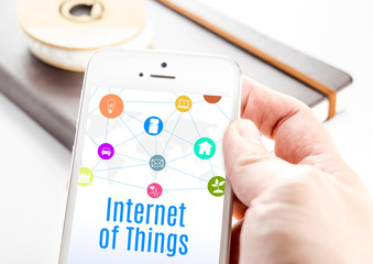 Close up hand holding smartphone with Internet of things word an