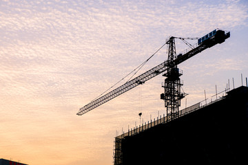 Silhouette of sunset scene with tower crane on the construction