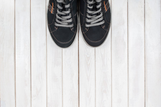 Pair of black sneakers on white wooden background. View from abo