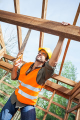 Construction Worker Cutting Wood With Handsaw At Site