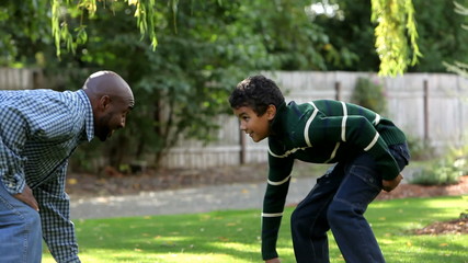 African American father and son playing with a football 