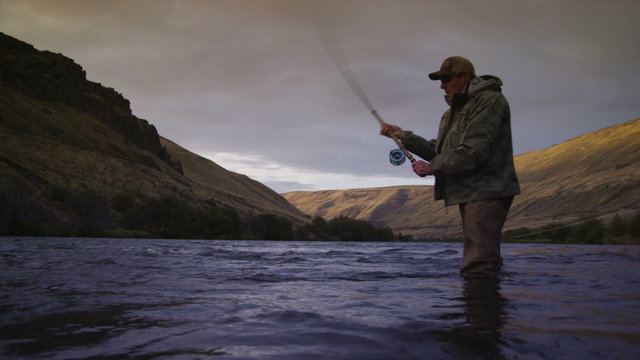 Man fly fishing in beautiful river at sunrise