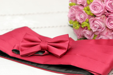 Bow tie and belt for the groom on bridal bouquet background.