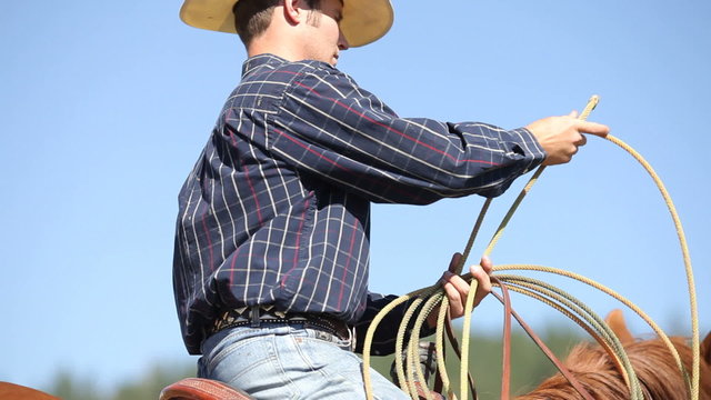 Cowboy on horse prepares lasso