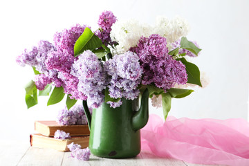 Beautiful lilac in pitcher on white wooden background