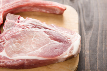 Fresh pork chops or cutlets on wooden background.