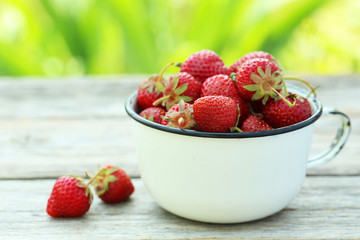Strawberries berry in cup on grey wooden background