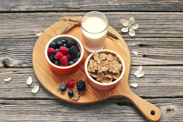 Muesli with milk and berry on wood plate