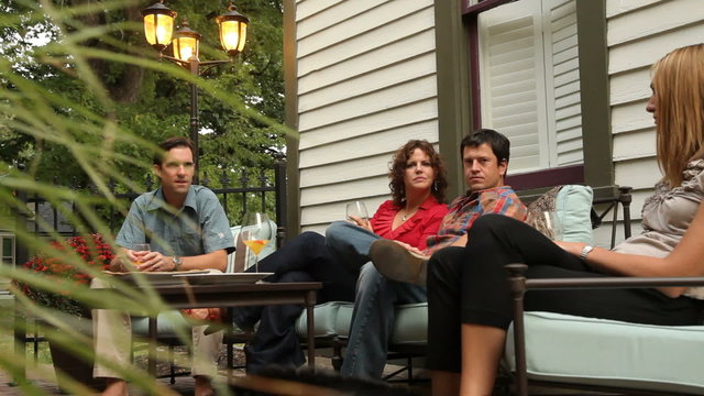 Group of people sitting on patio together talking and laughing