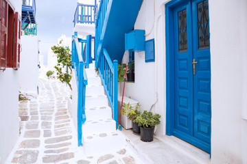 Streetview of Mykonos town with white street, stairs and blue door, Greece