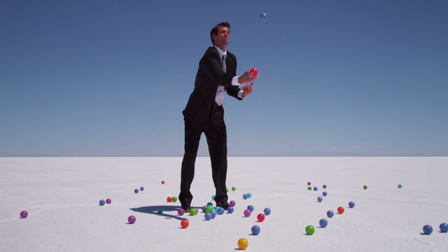 Businessman juggling colored balls at salt flat