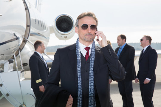 executive manager in front of corporate jet using a smartphone