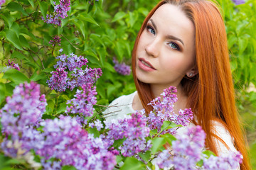 beautiful cute sexy red-haired girl with long hair in a white dress with a bouquet of lilac in the hands of
