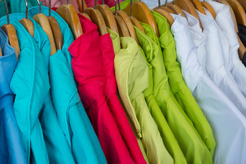 Rainproof jackets in bright colors on a rack for sale.