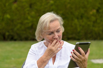 Rentnerin mit einem Tablet in ihrem Garten
